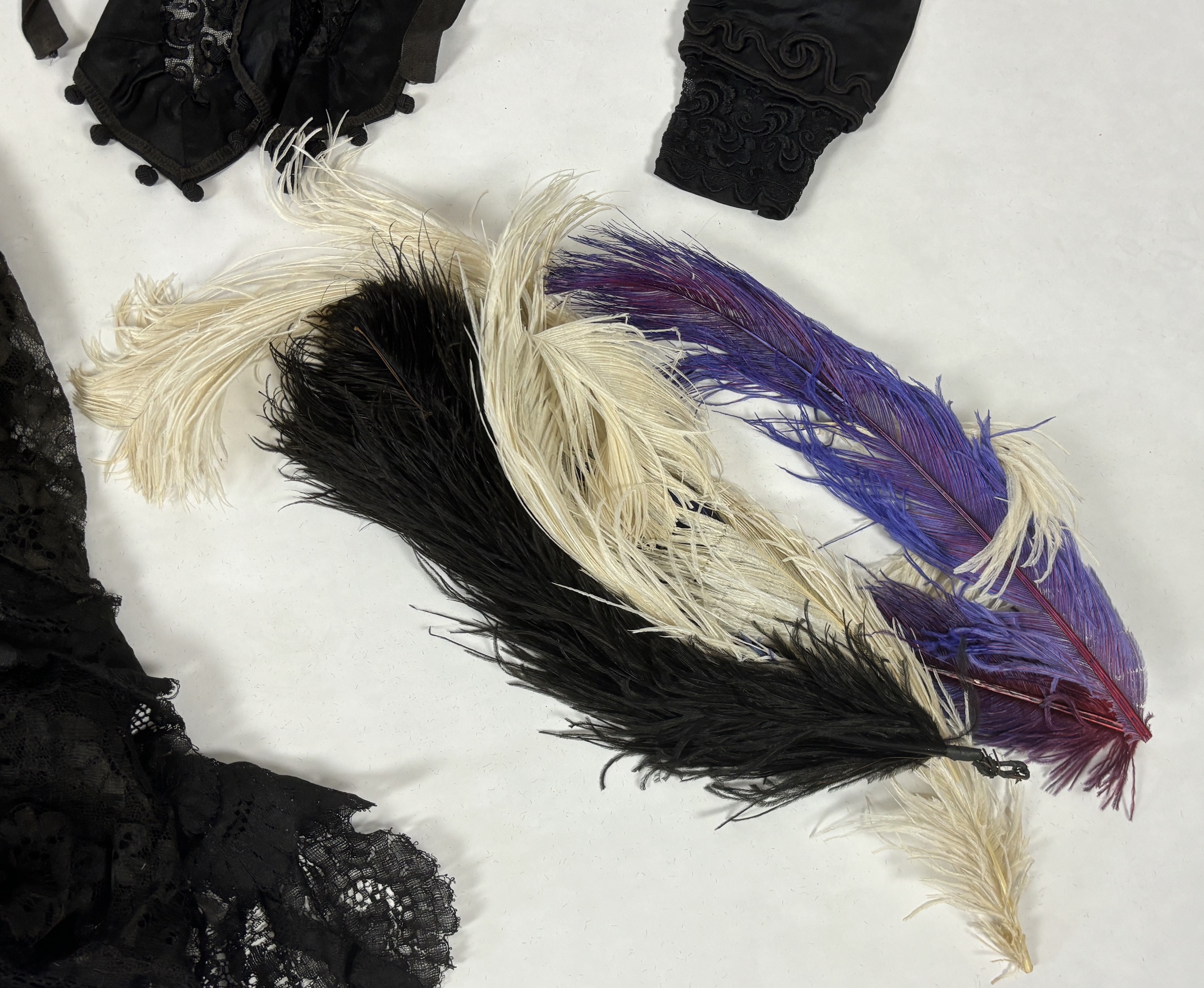 Two lady's Victorian black satin and lace, bead trimmed bodices, together with a black lace cape, a black satin cape, a small collection of coloured feathers and a child’s white worked pinafore